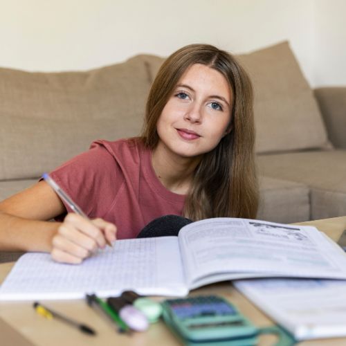 teen girl sitting on floor writing